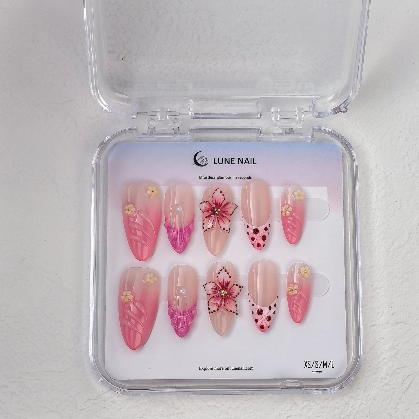 Clear travel case showcasing Petal Fiesta press-on nail kit on gradient backing card
