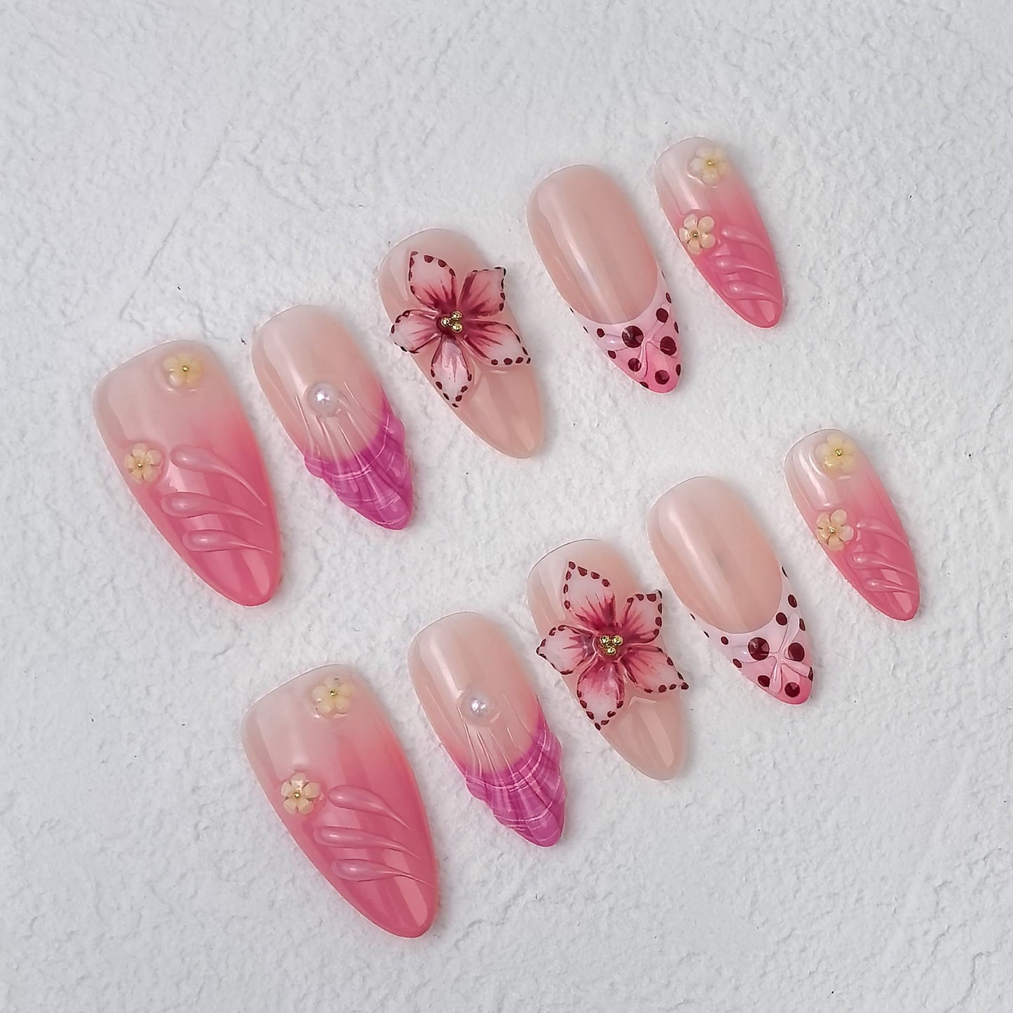 Petal Fiesta press-on nails scattered at an angle, showing heart-tip French designs and layered petals.