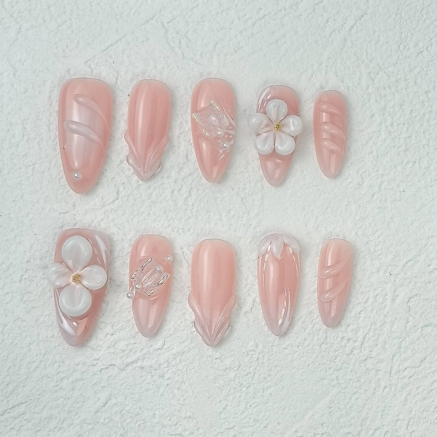 Pink floral press-on nails with 3D flowers and pearl details, flat layout