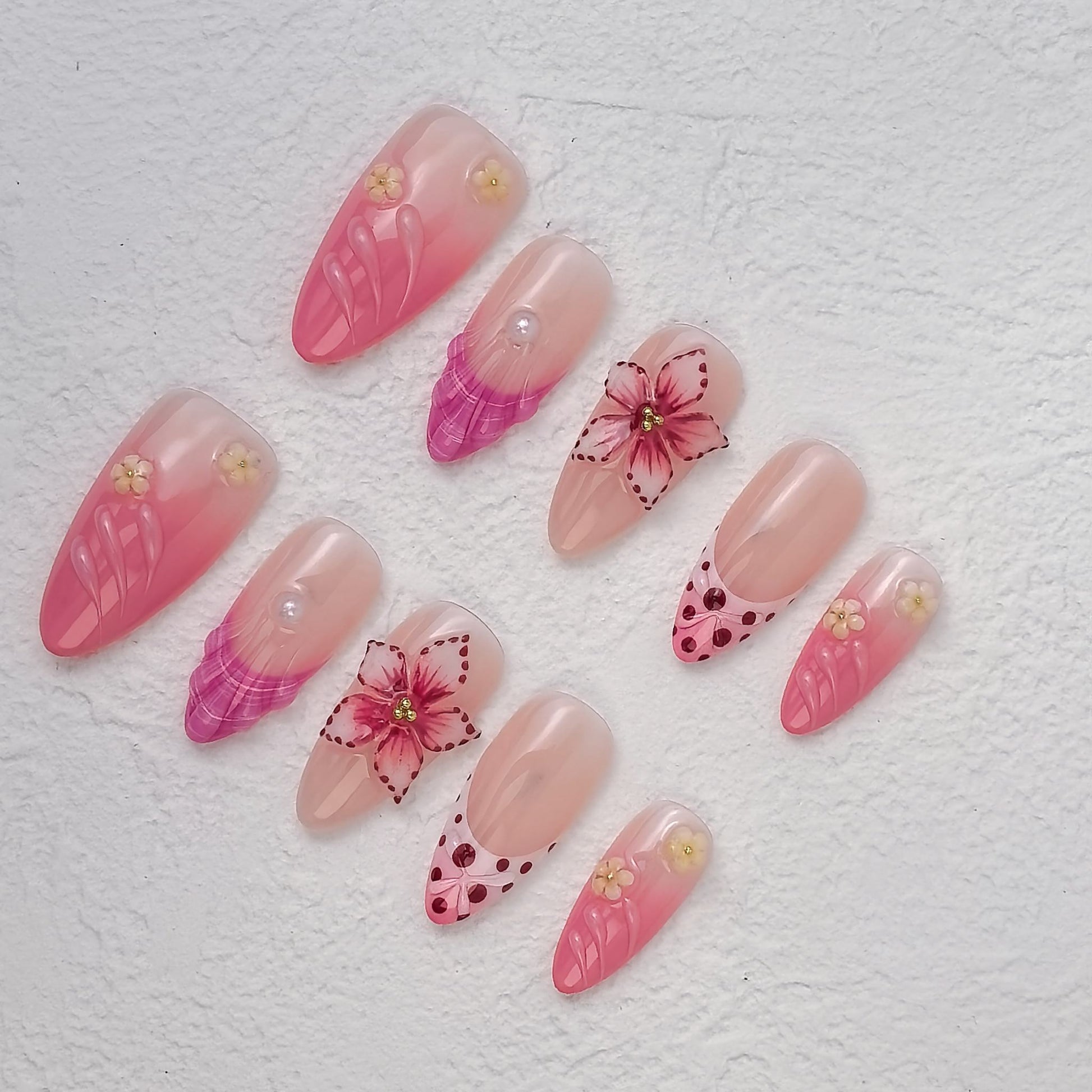 Close top-view of Petal Fiesta nails featuring hot-pink feathered tips, dotted hearts and raised flowers