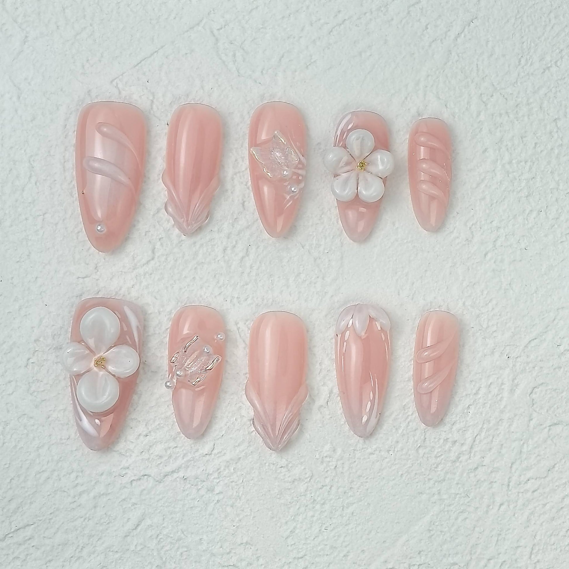 Pink floral press-on nails with 3D flowers and pearl details, flat layout